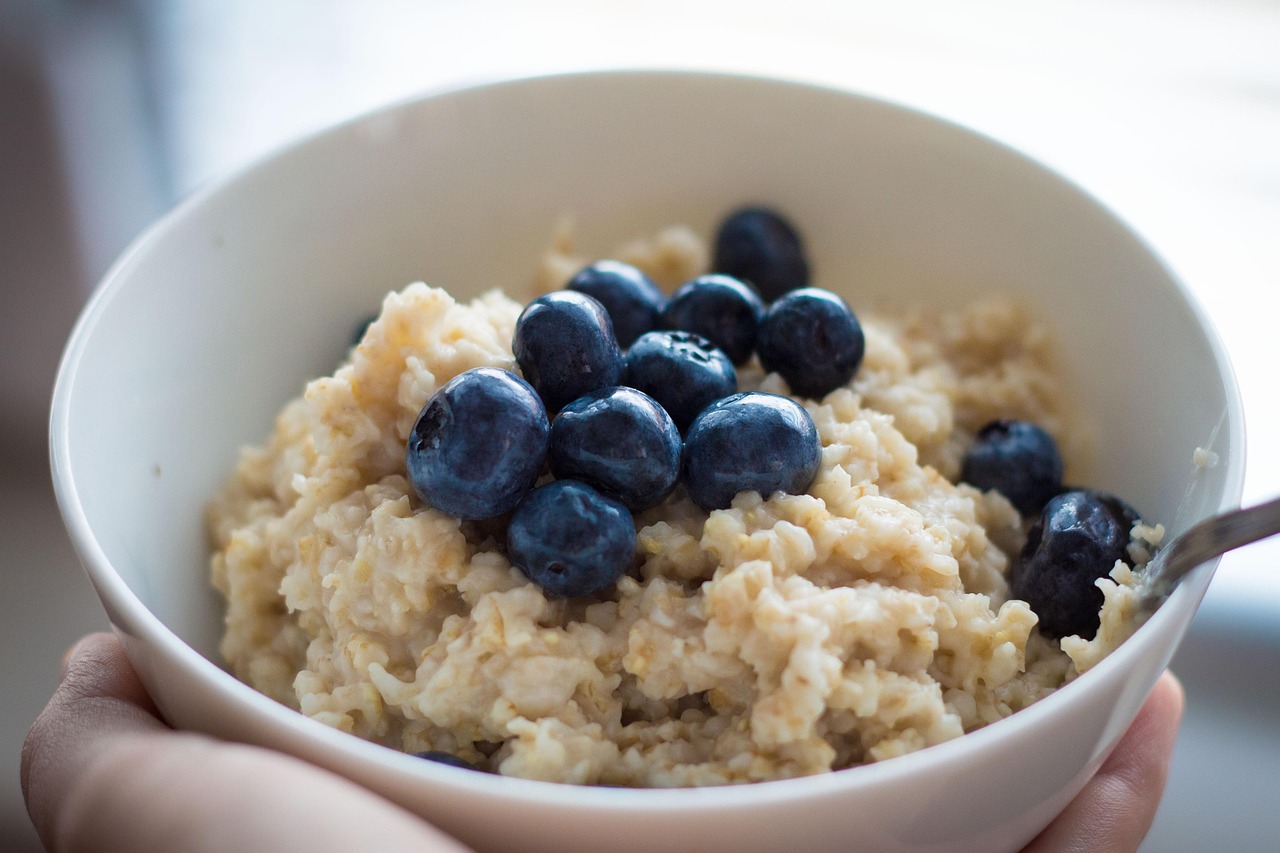 Bowl of oatmeal topped with fresh blueberries and a spoon on the side.