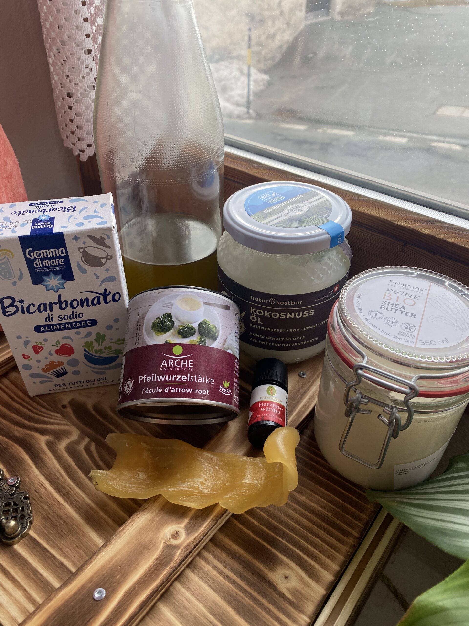 Ingredients for homemade natural deodorant, including beeswax, shea butter, coconut oil, and other DIY supplies arranged on a wooden countertop.