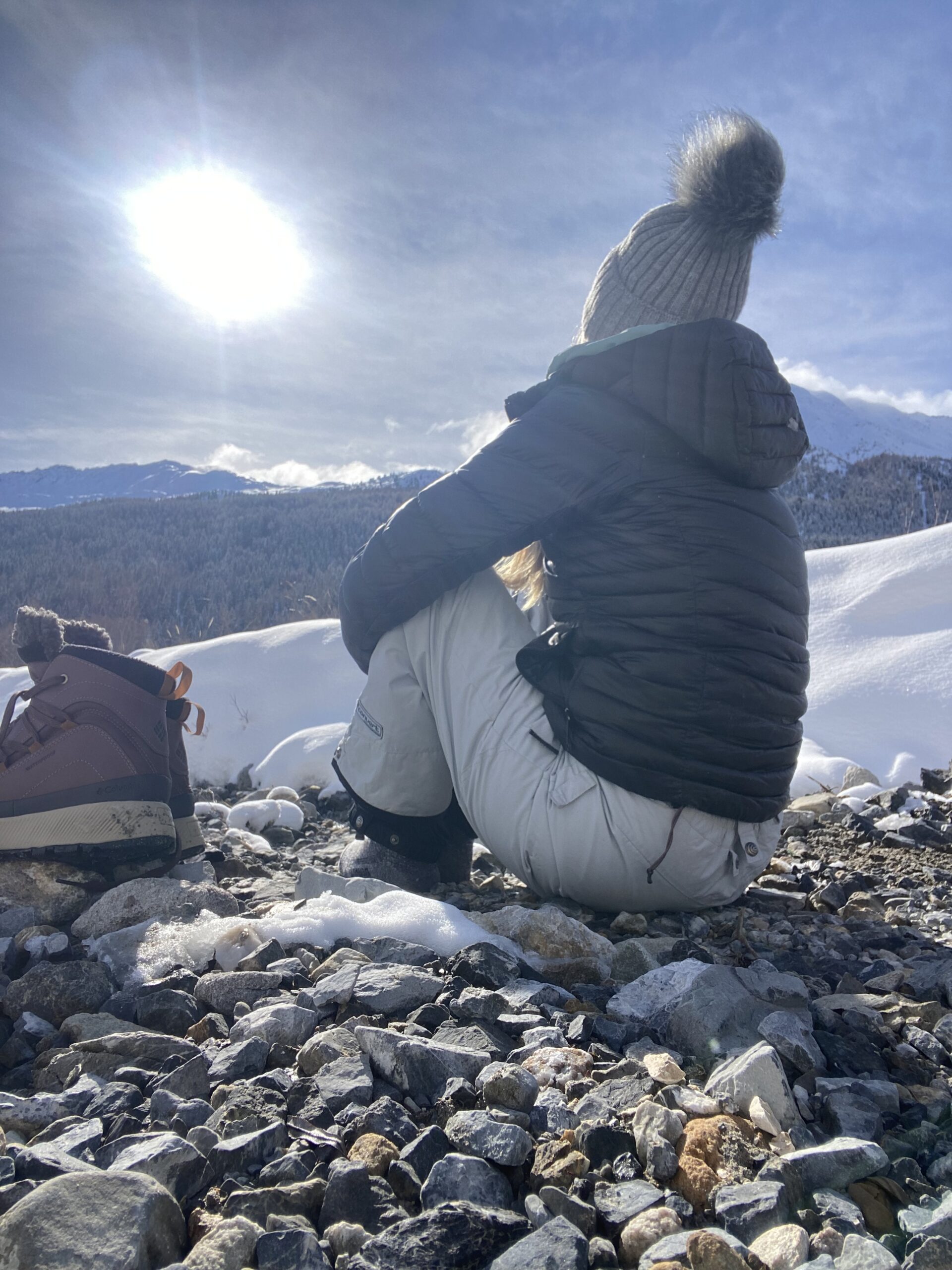 Woman sitting in quiet reflection overlooking the snowy Swiss Alps.